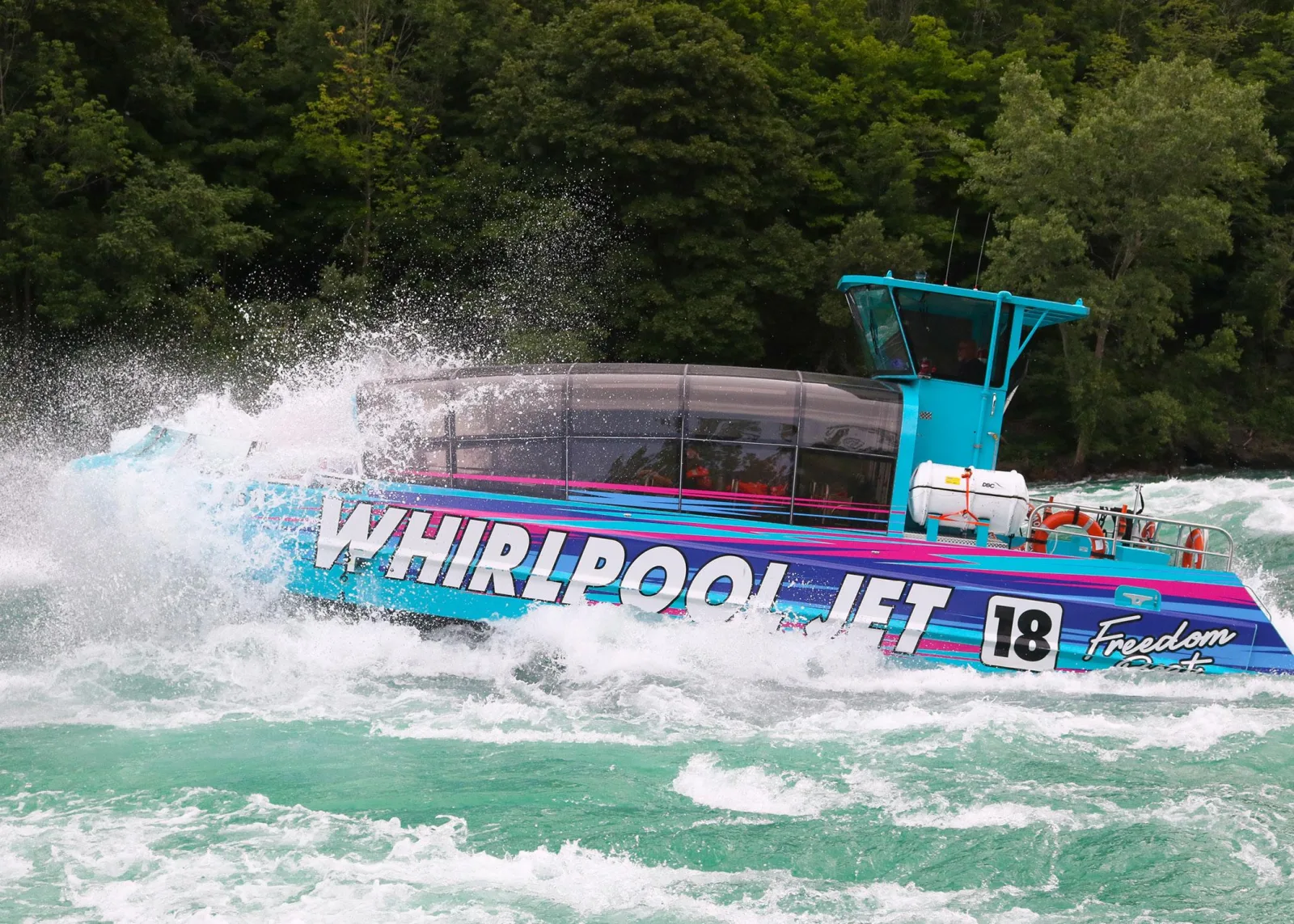 The domed Whirlpool Jet Freedom Boat, its glass canopy closed, throwing spray as it drives through the Class 5 rapids