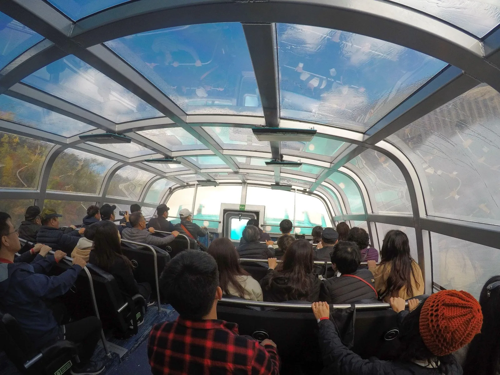 Inside the domed Freedom Jet: passengers seated dry under the glass canopy with the autumn gorge visible through the windows