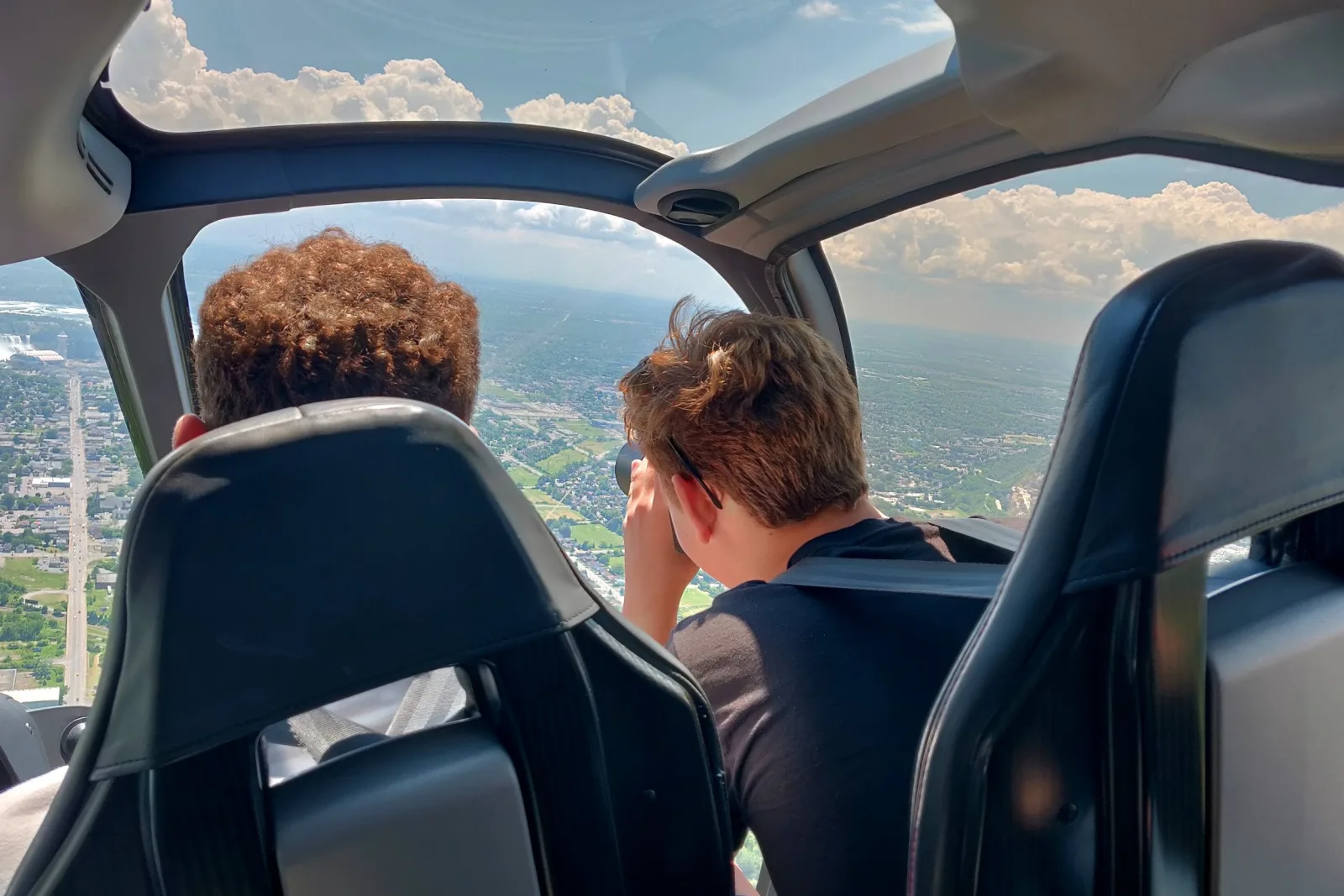 View forward from the passenger seats as the helicopter flies over the Niagara region, farmland and town spread out below the bubble windscreen