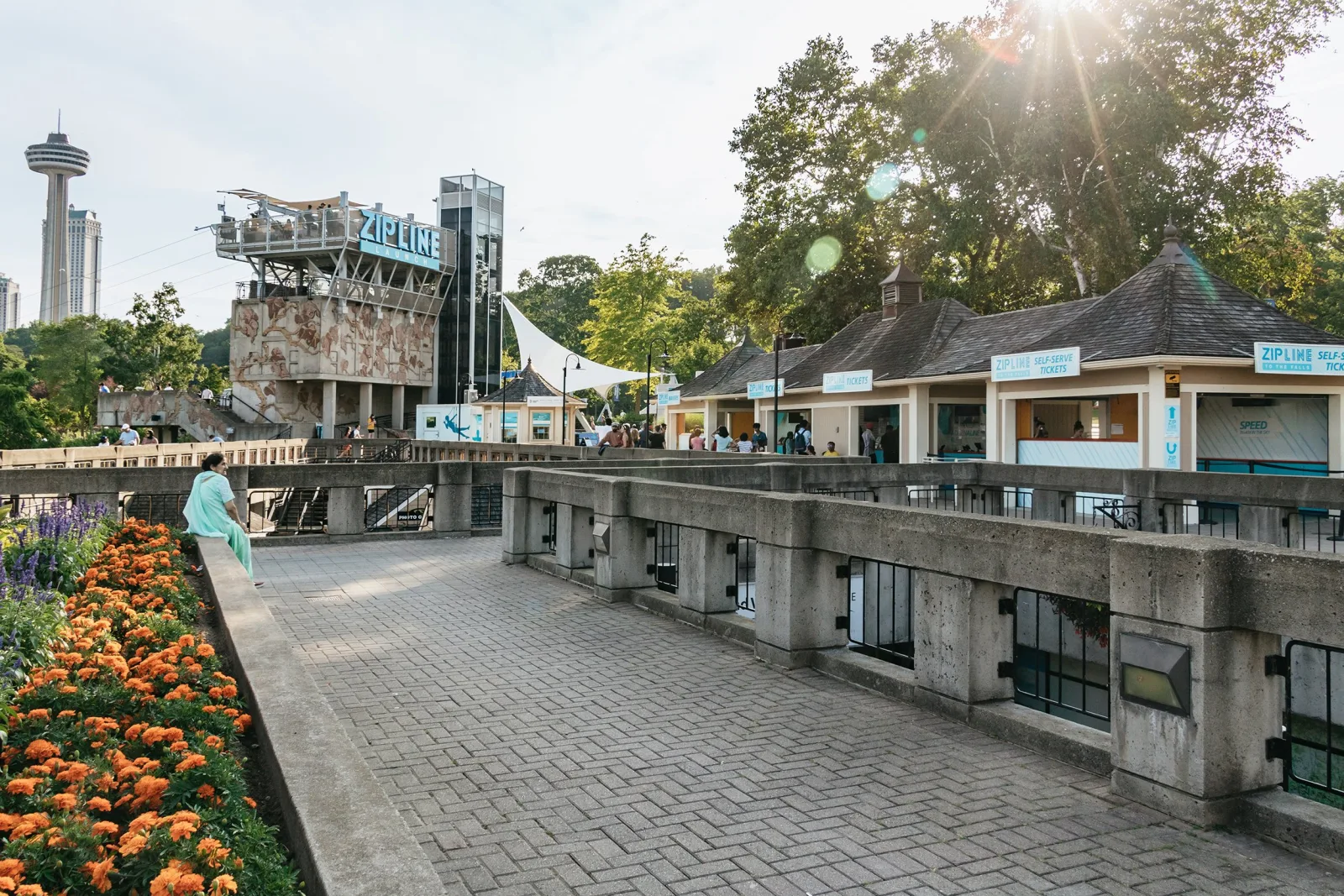 The Zipline to the Falls launch tower and self-serve ticket kiosks at the bottom of Clifton Hill, the Skylon Tower on the skyline behind
